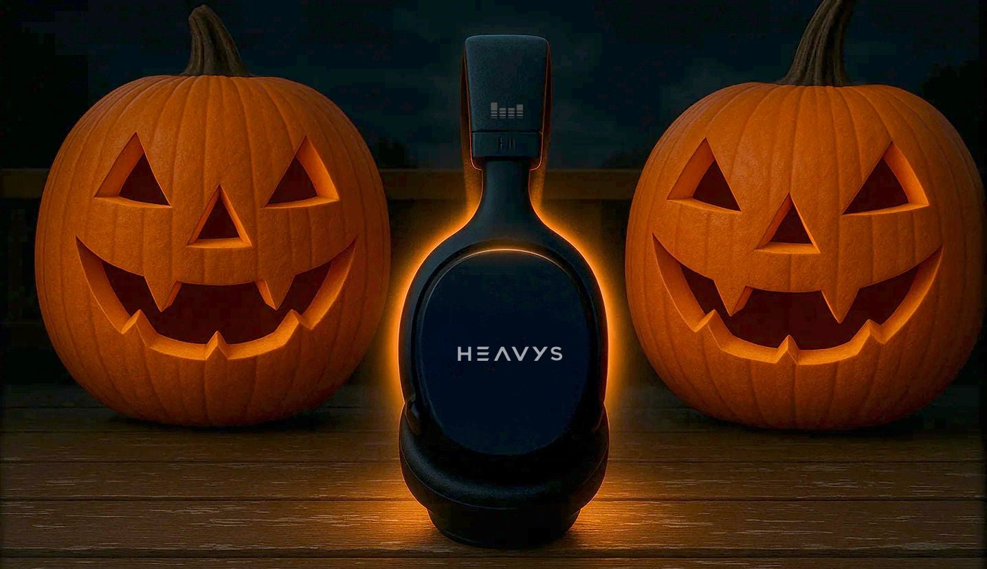 Black bottle labeled 'HEAVYS' between two carved pumpkins on a wooden surface at night.