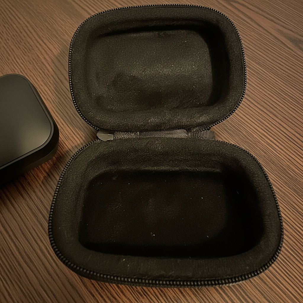 Black hard-shell travel case on a beige surface. earbuds